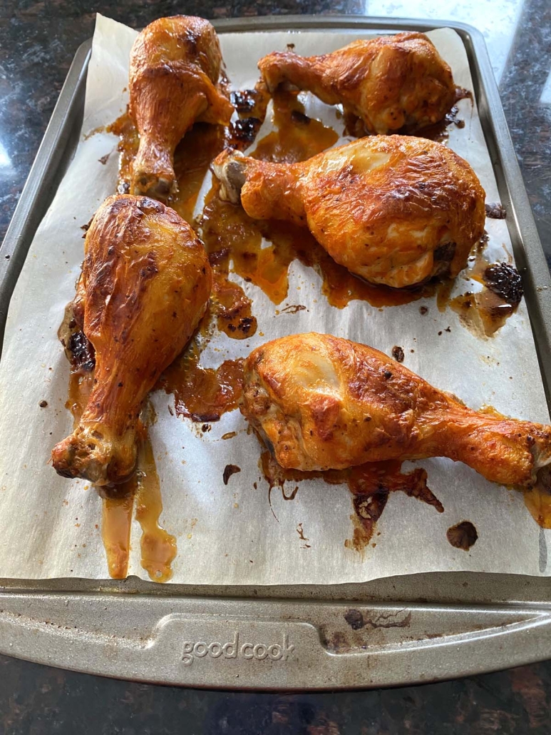 close-up of golden brown drumsticks topped with buffalo sauce