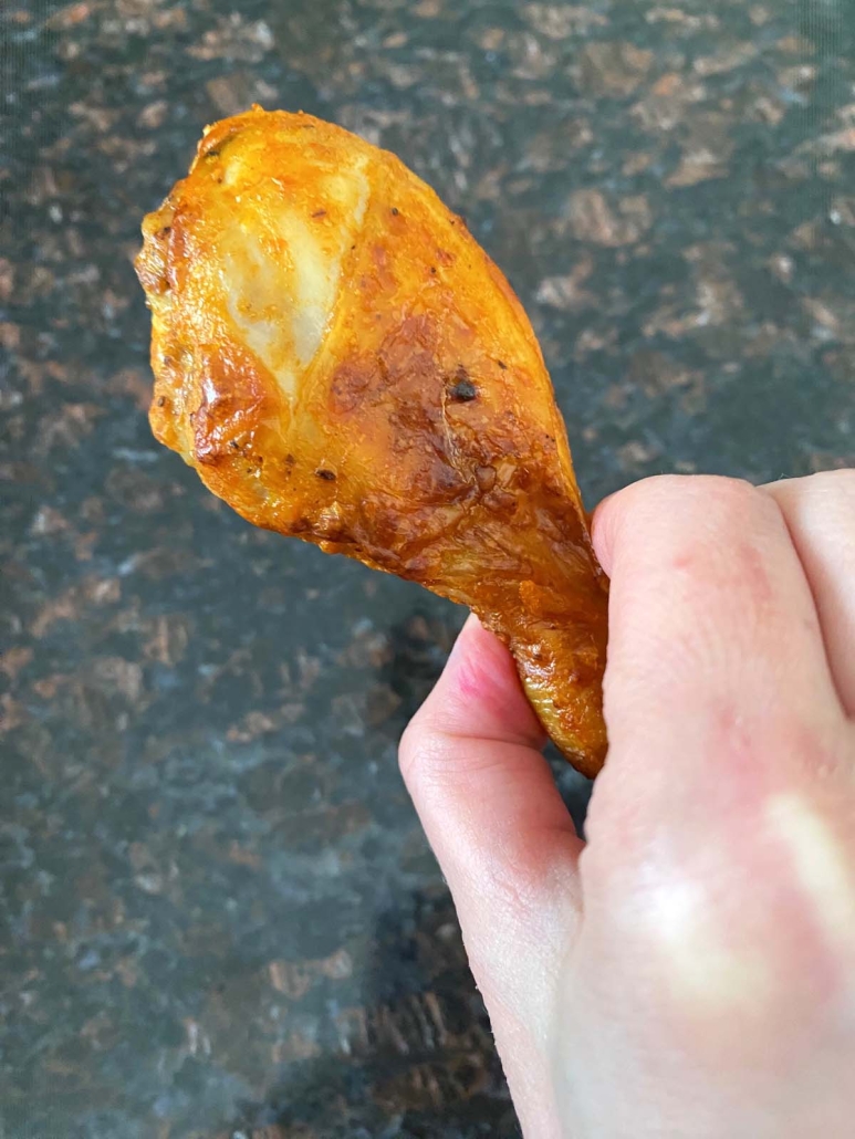 hand holding oven baked buffalo drumstick