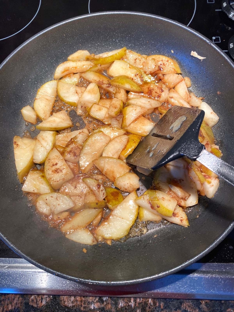 sliced pears topped with cinnamon and honey, cooking in a skillet