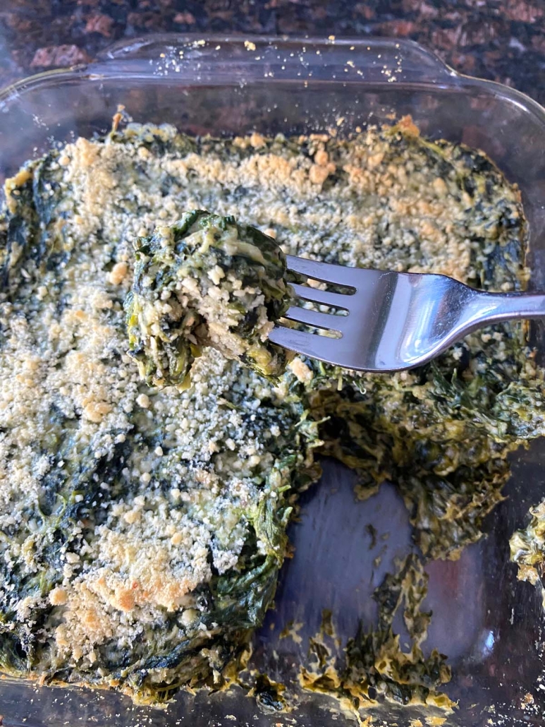 fork holding piece of cheesy spinach from Spinach Casserole