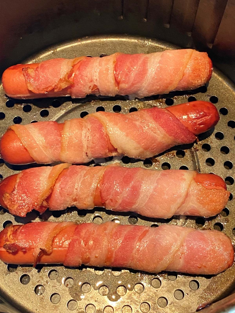 bacon wrapped hot dogs cooking in air fryer
