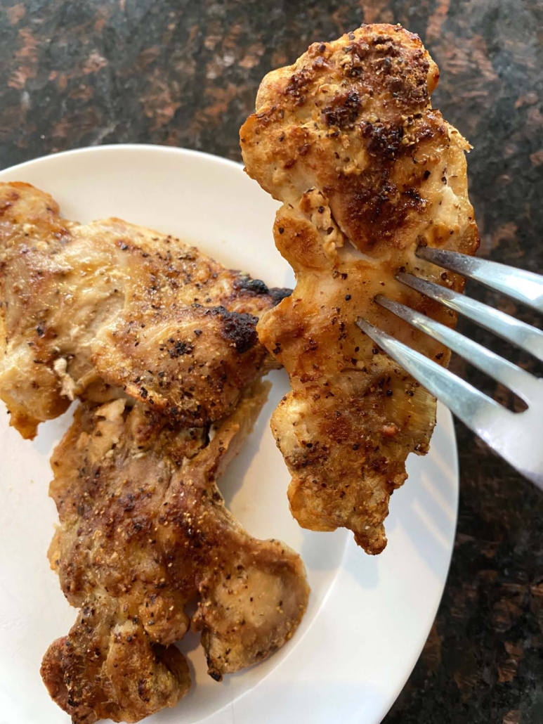 fork holding piece of seasoned chicken thigh cooked in air fryer
