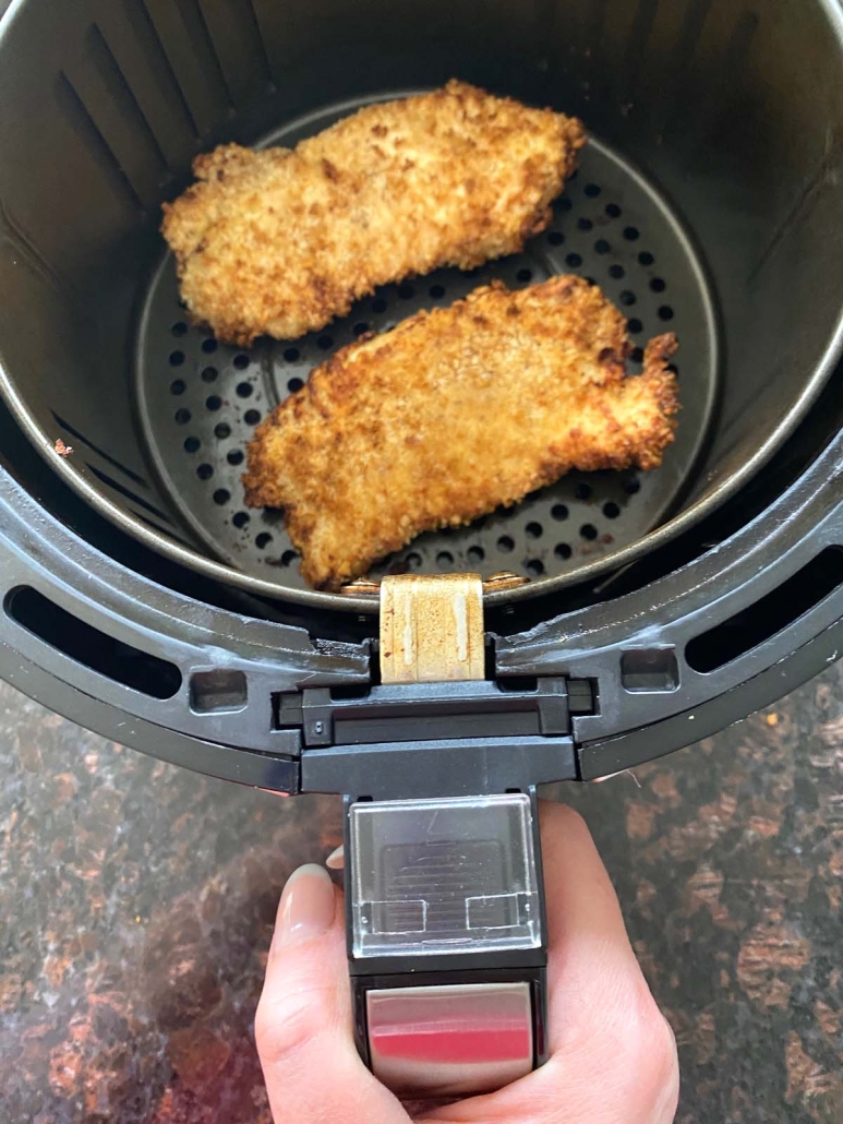 hand holding air fryer basket with Panko Chicken inside