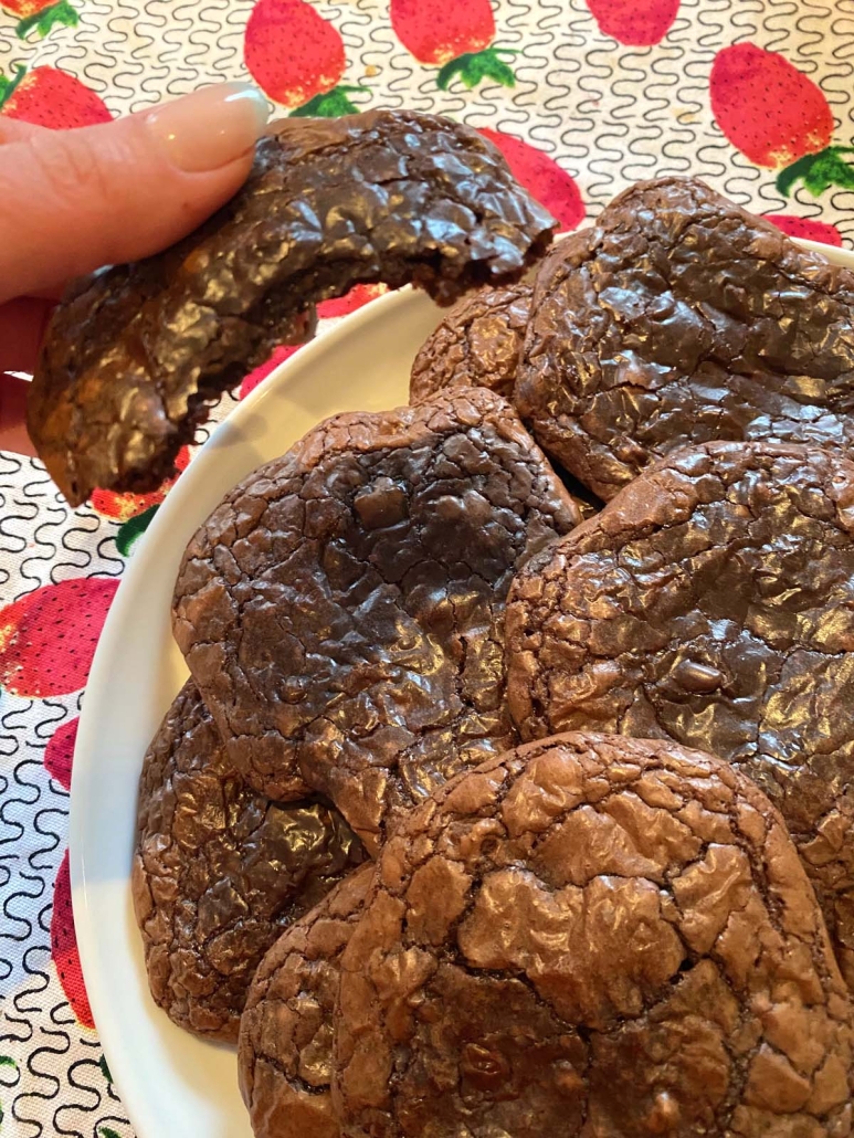 hand holding Brownie Mix Cookie next to plate of cookies