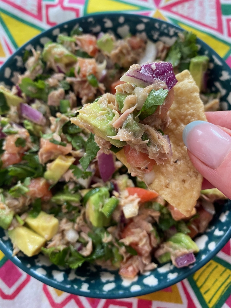 hand holding chip with Canned Tuna Ceviche on top