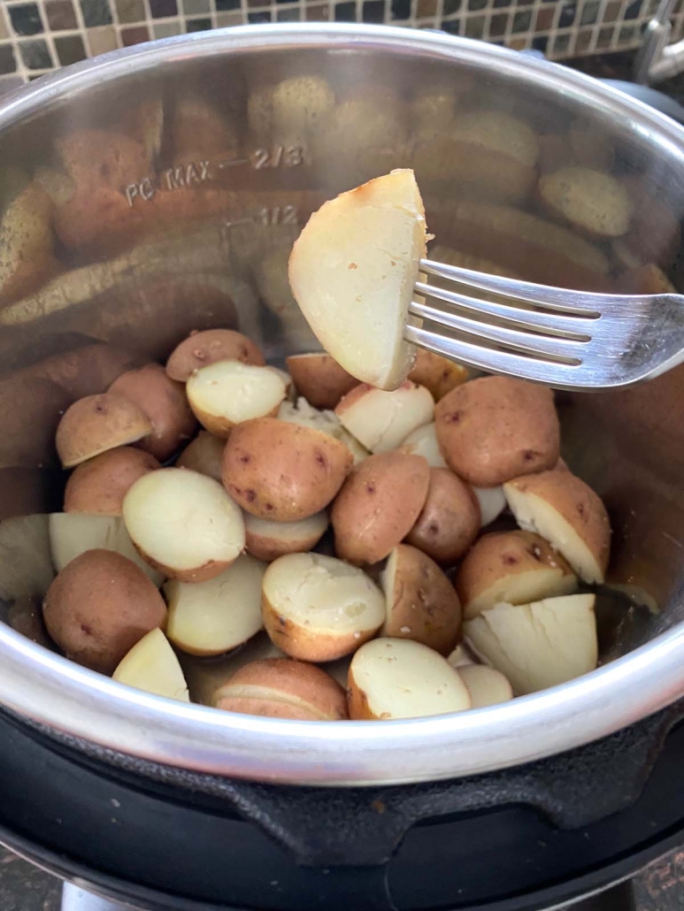 fork holding piece of red potatoes cooked in the instant pot