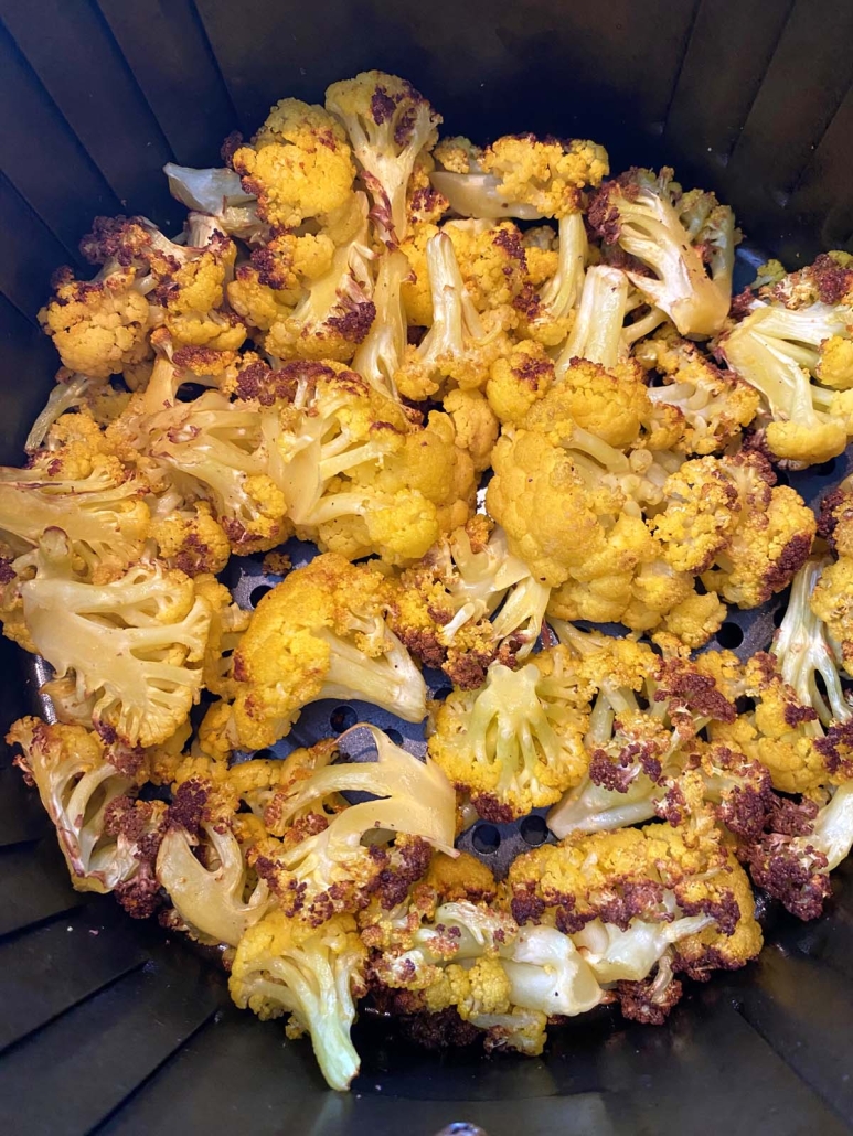 crispy orange cauliflower florets cooking in an air fryer