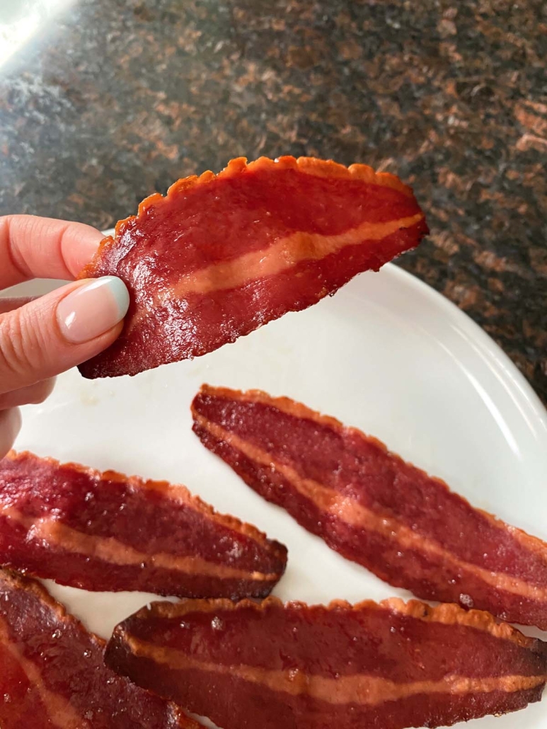hand holding slice of oven baked Turkey Bacon