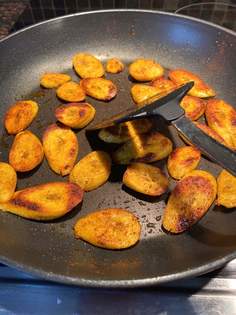 plantain slices cooking in a skillet