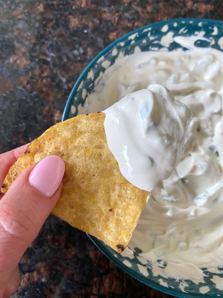 hand holding chip with sour cream and onion dip