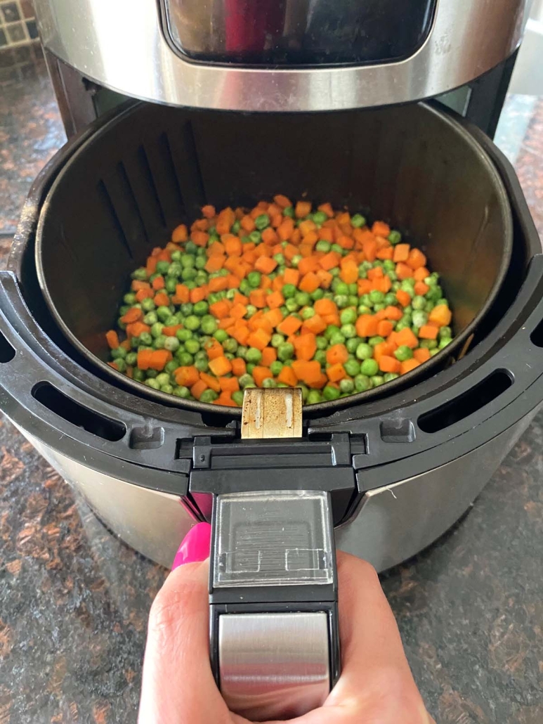 air fryer opened to show peas and carrots inside