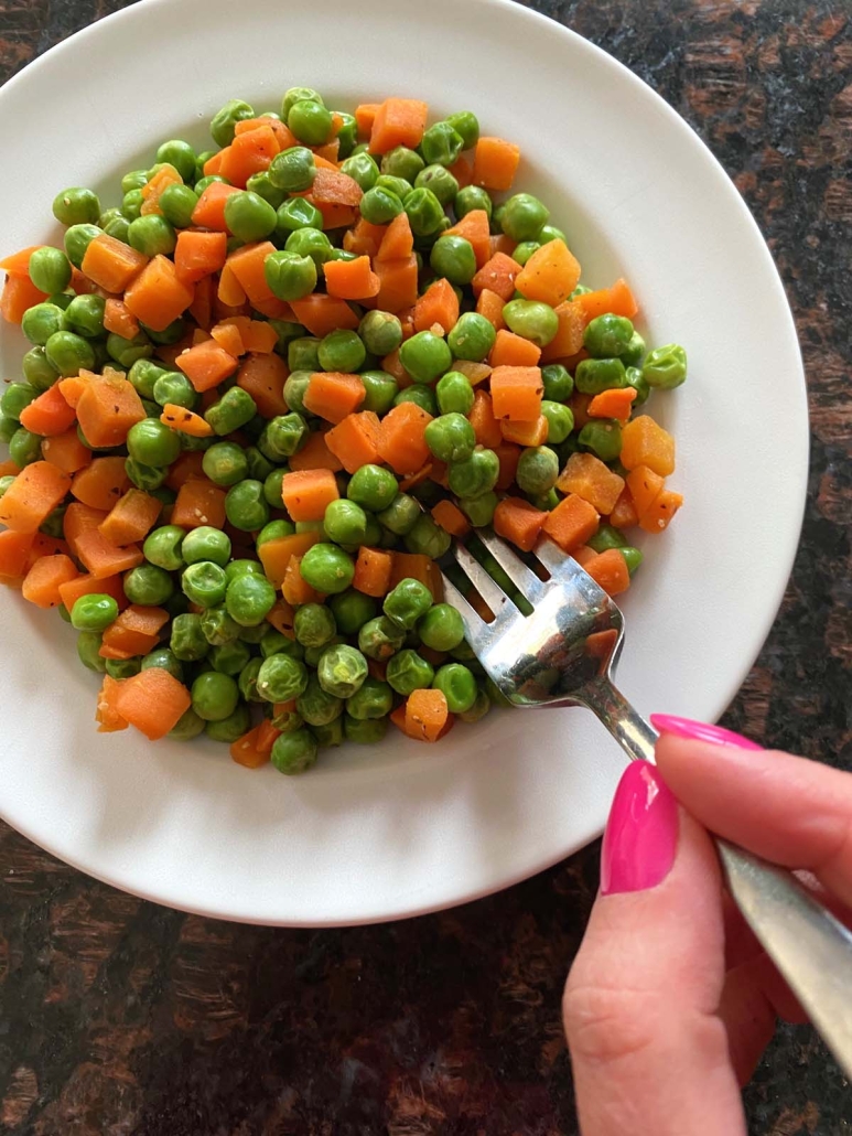 fork in cooked peas and carrots
