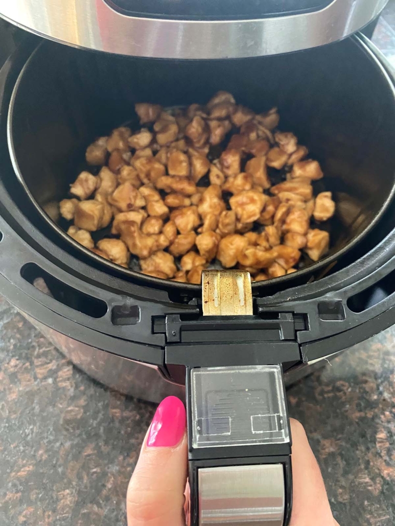 air fryer containing pieces of chicken breast with teriyaki sauce