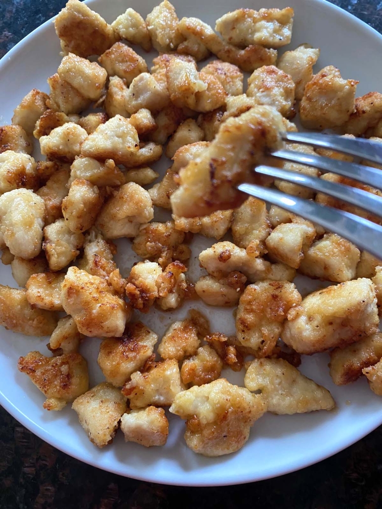 fork holding piece of golden brown Honey Butter Fried Chicken