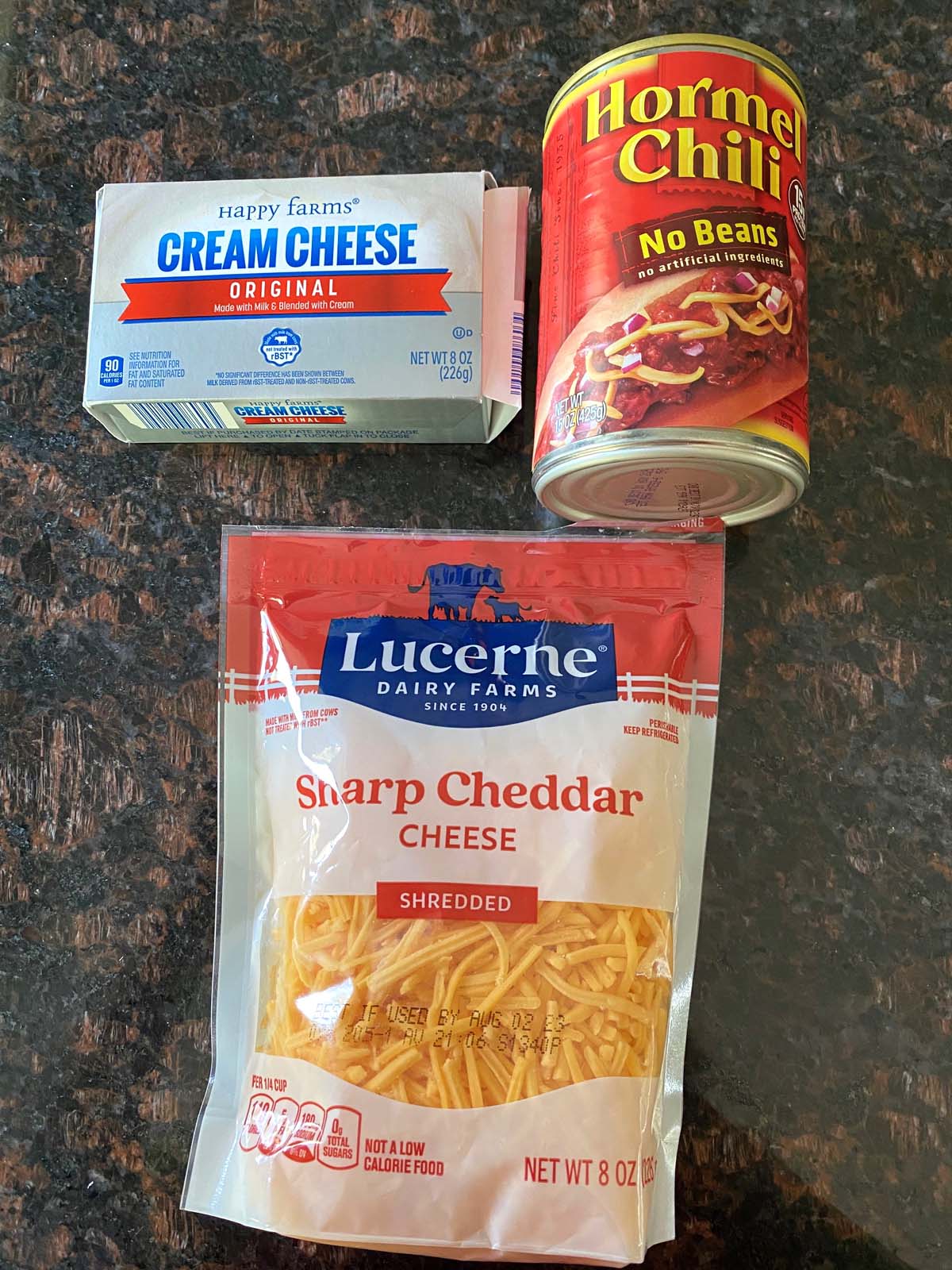 Can of chili, block of cream cheese, and package of shredded cheddar cheese. 
