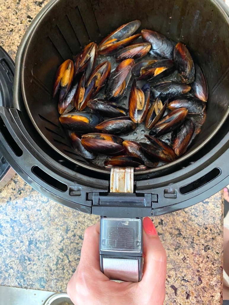 hand holding air fryer with mussels