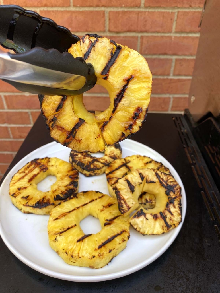 tongs holding slice of Grilled Pineapple