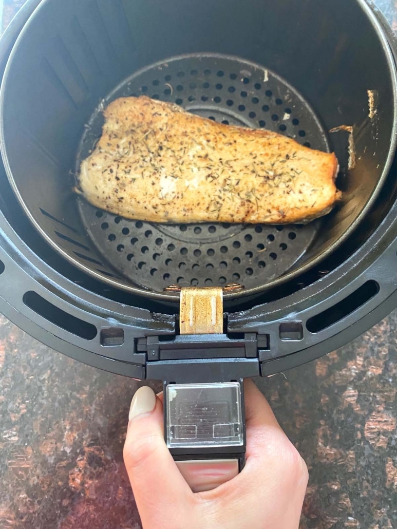 hand holding air fryer basket with trout inside
