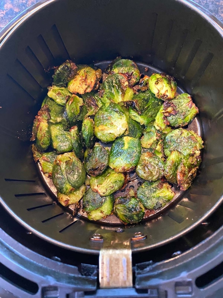 air fryer basket with seasoned Brussels Sprouts inside