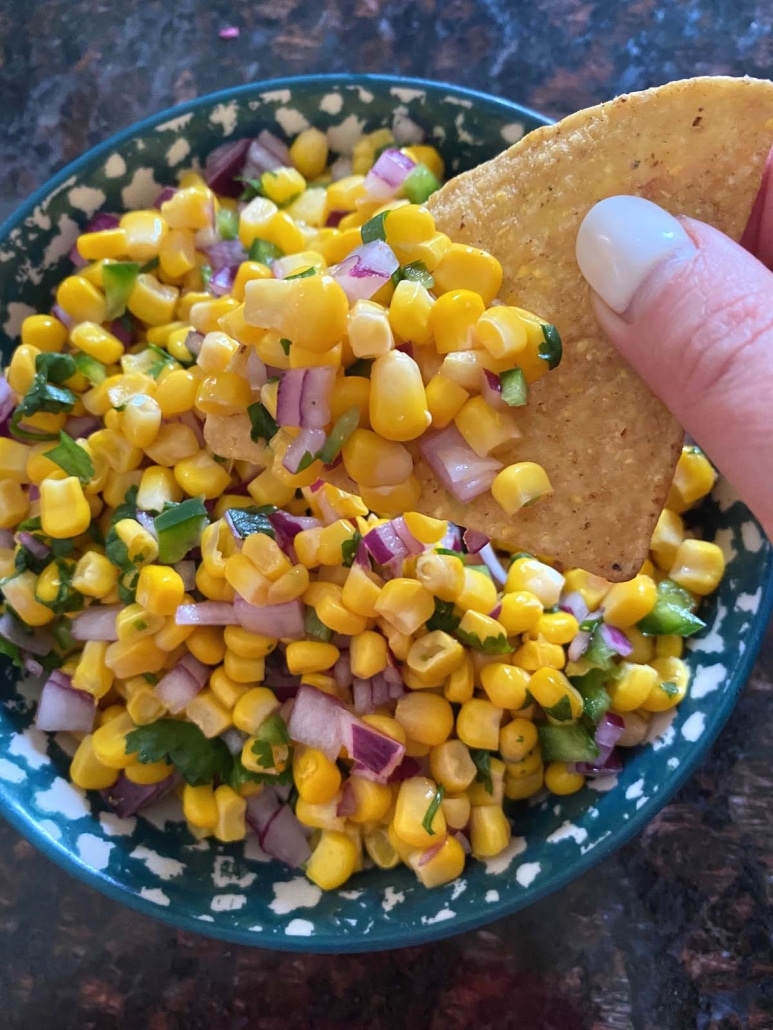 dipping a chip into Chipotle Corn Salsa Copycat Recipe