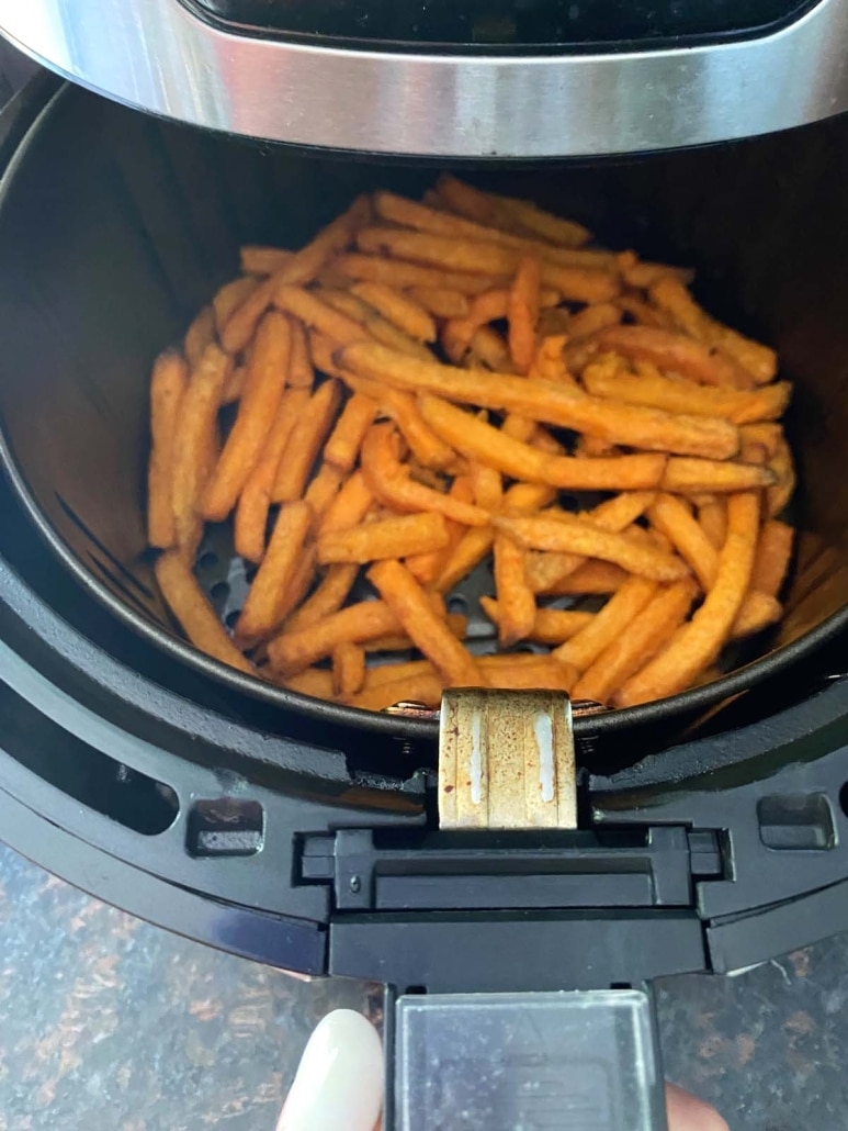 air fryer opened to show frozen Trader Joe’s Sweet Potato Fries crisping up inside