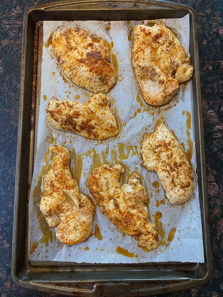 seasoned, thin chicken breasts on a baking sheet