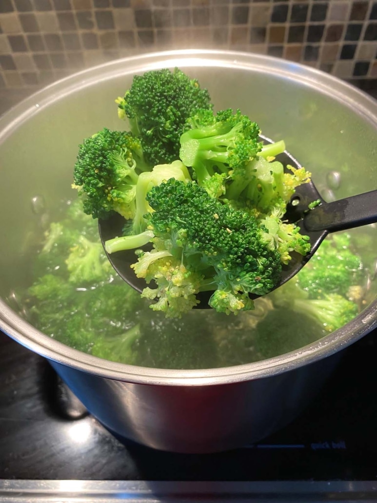 slotted spoon removing cooked broccoli from pot