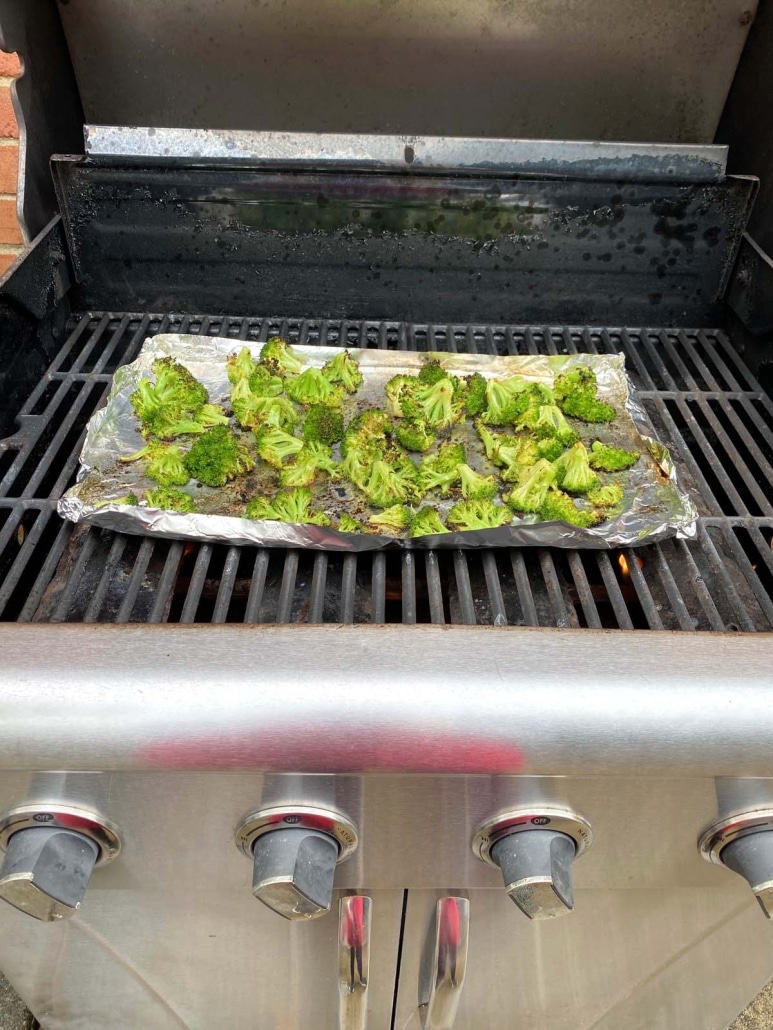 grill opened to show broccoli cooking inside