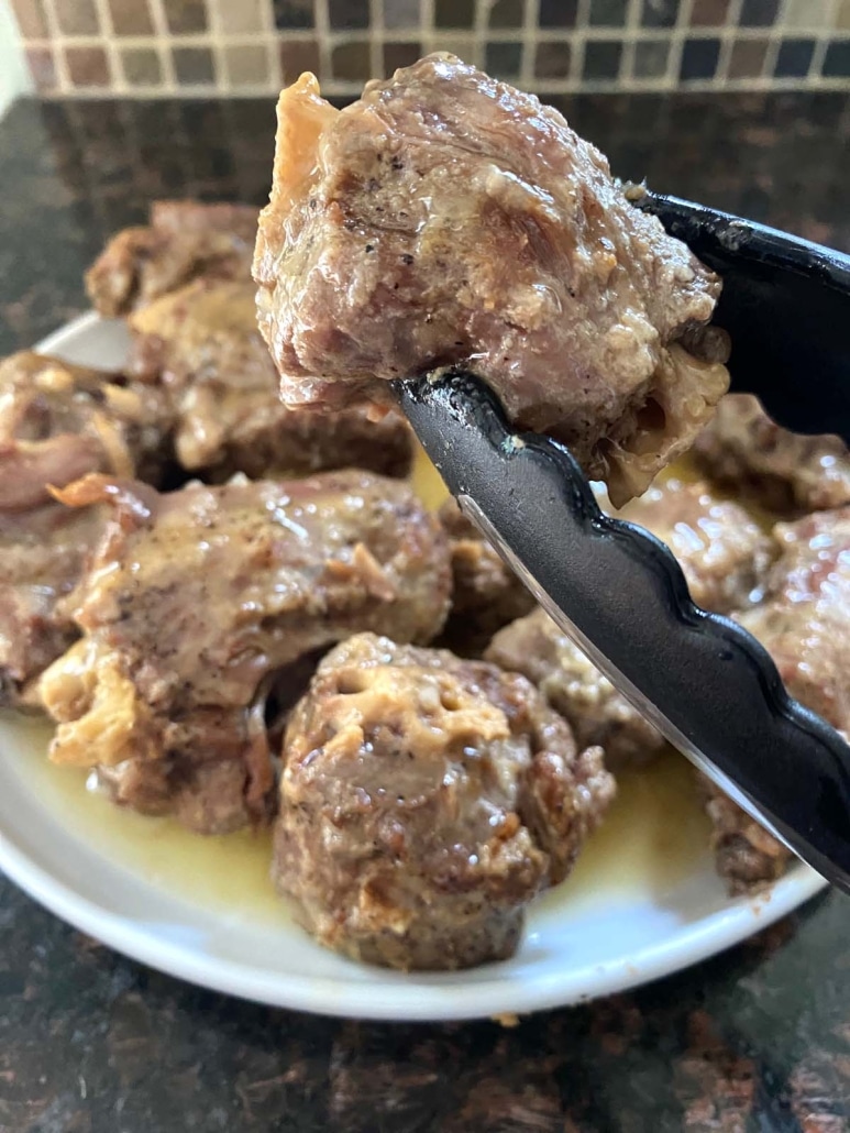 tongs holding tender turkey neck in front of plate