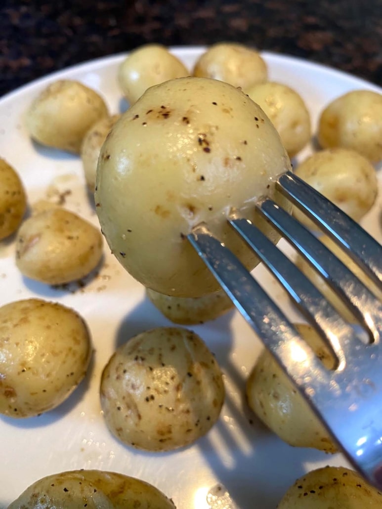 fork holding seasoned, cooked small potato
