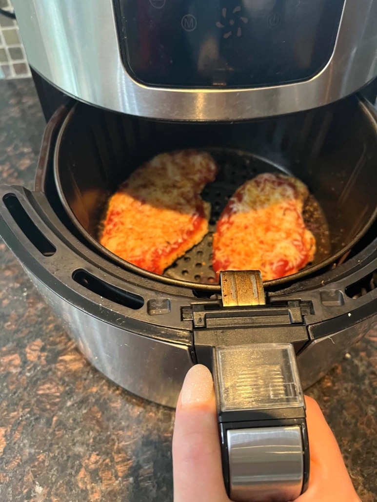 air fryer opened to show Chicken Parmesan cooking inside