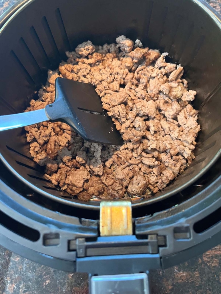 spatula mixing up ground turkey in the air fryer basket