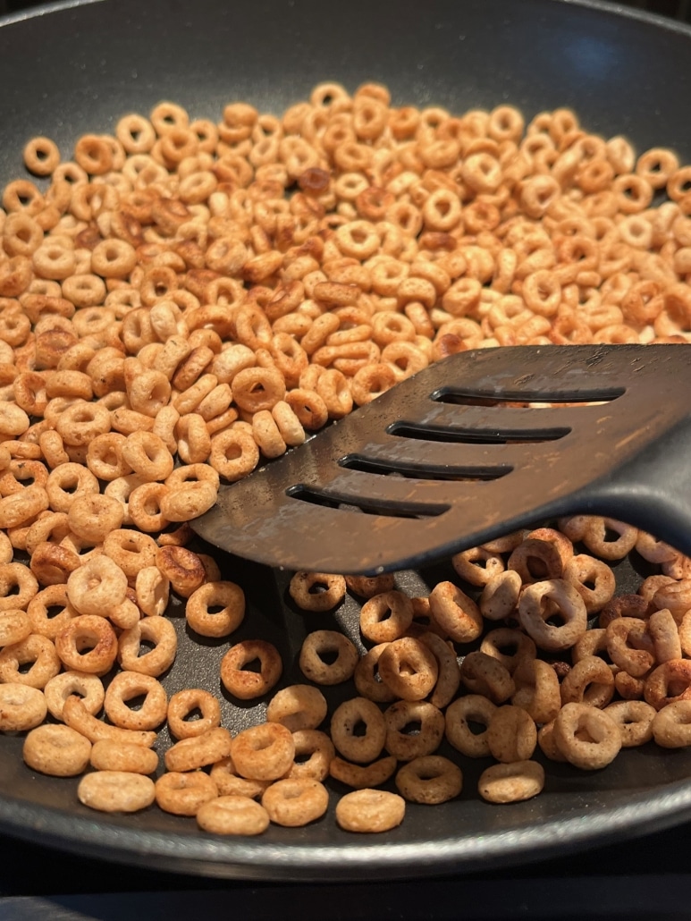spatula mixing Cheerios with melted butter