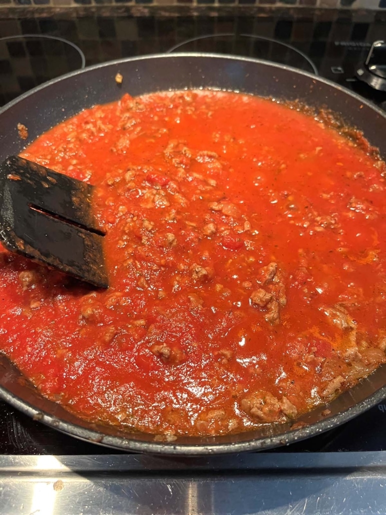 stirring up Ground Turkey Bolognese Sauce in a pan