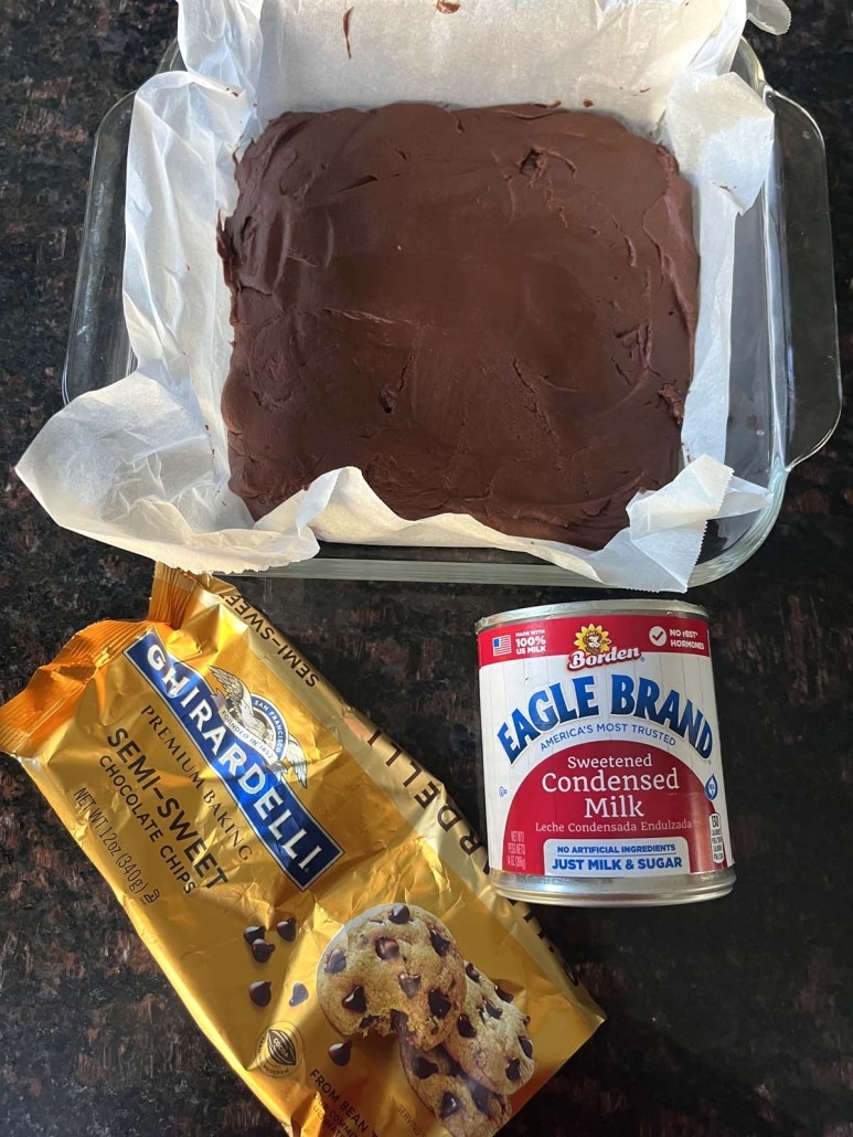 2-Ingredient microwave fudge in a dish next to a bag of chocolate chips and a can of sweetened condensed milk