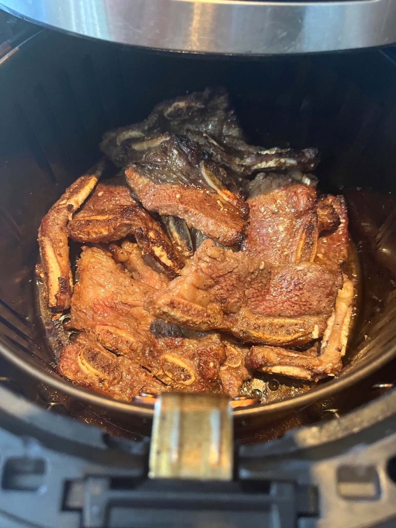 air fryer opened to show ribs cooking inside
