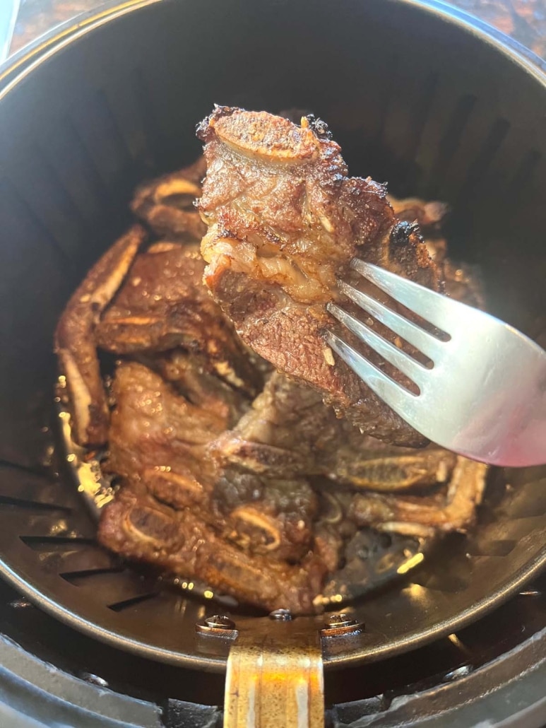 fork holding piece of short ribs cooked in air fryer