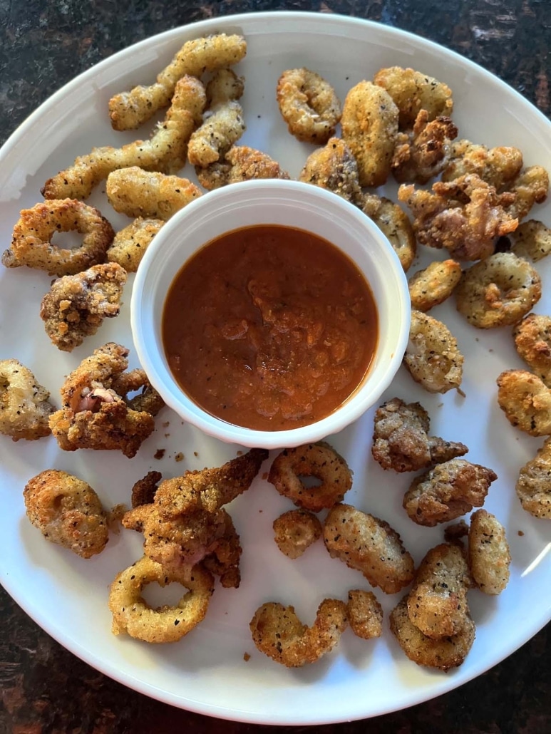 plate of breaded calamari surrounding a bowl of dipping sauce