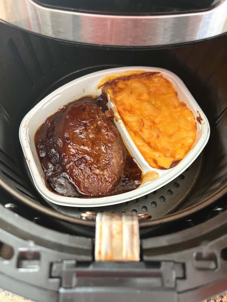 air fryer opened to show cooked Salisbury steak dinner inside