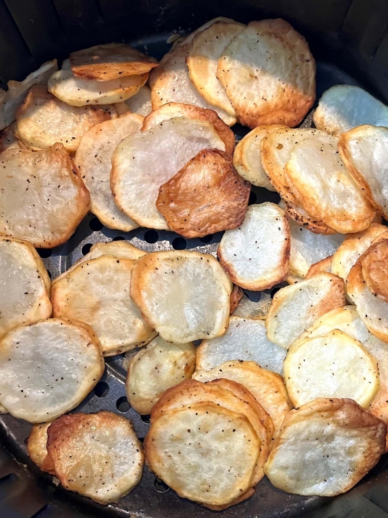 golden brown potato slices in an air fryer basket