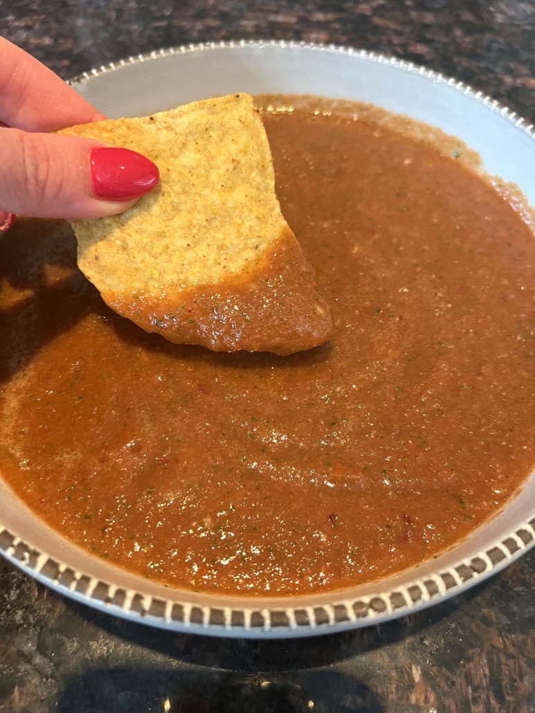 hand dipping a tortilla chip into Blender Salsa
