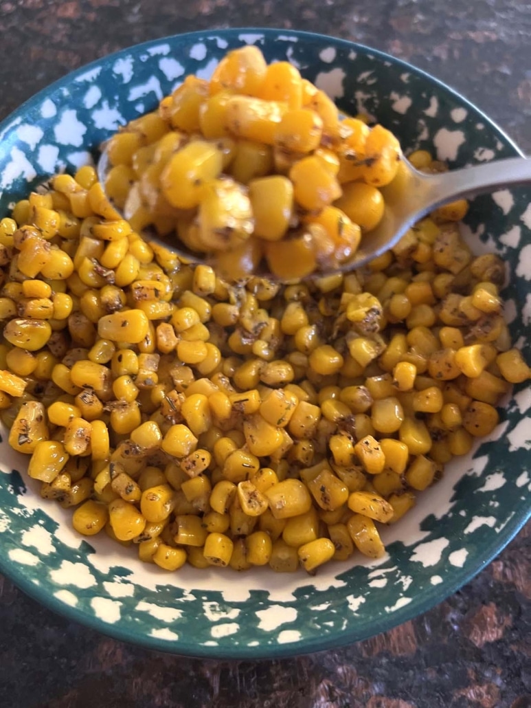 spoon scooping up seasoned, buttered corn