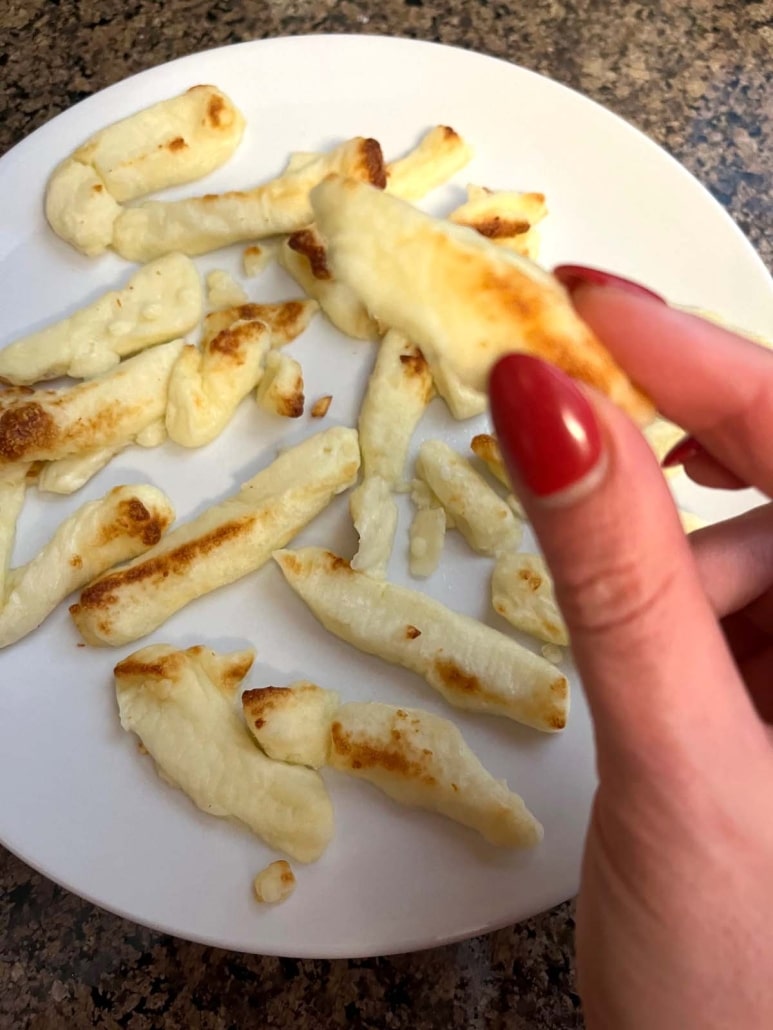 hand holding a cooked cheese fry