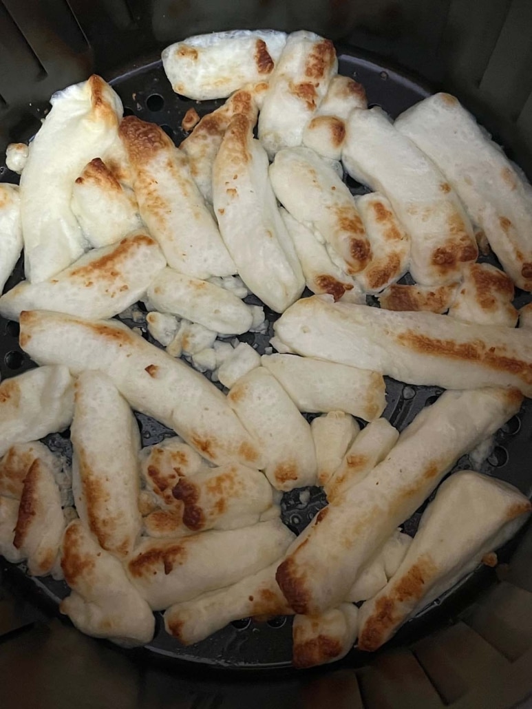 close-up of melted cheese fries in air fryer basket