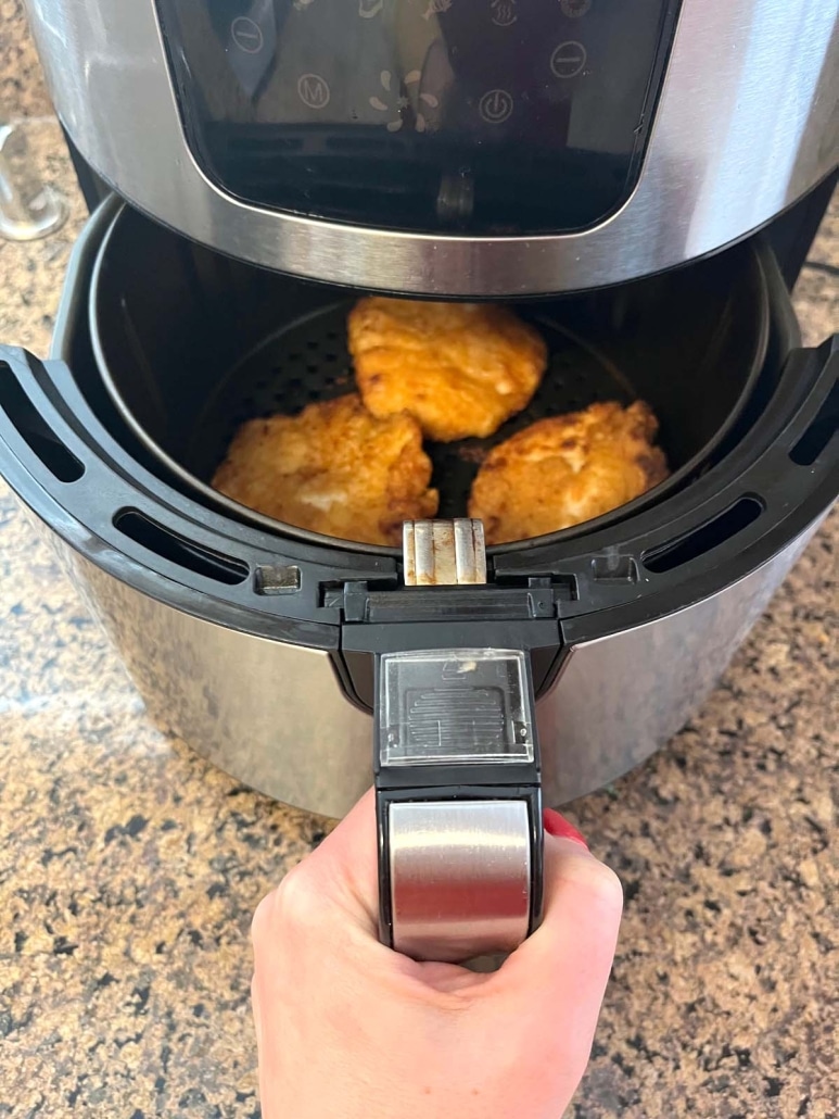 air fryer opened to show breaded chicken breasts cooking inside