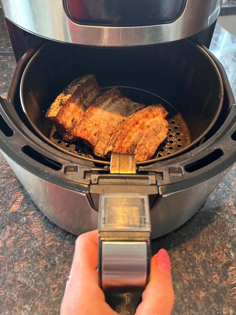 air fryer opened to show pork belly cooking inside