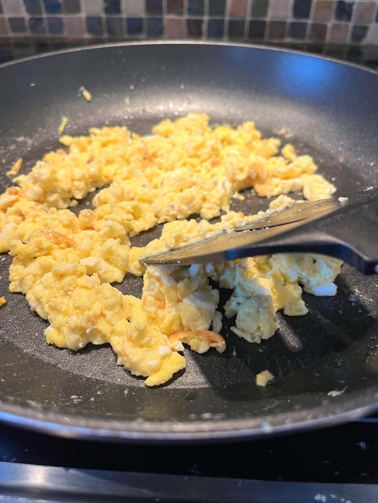 skillet with spatula scrambling up eggs