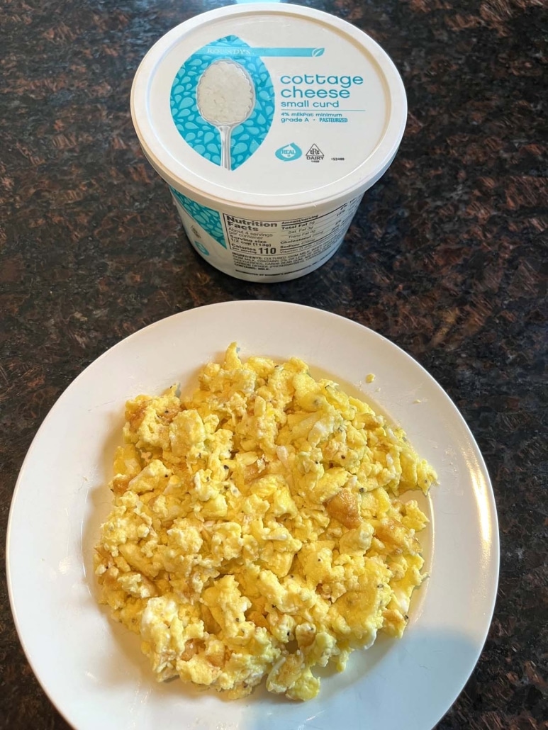 plate of cheesy scrambled eggs next to a container of cottage cheese
