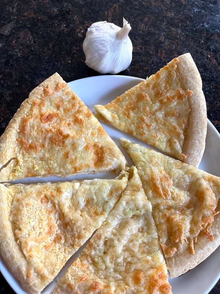 slices of Garlic Pizza on a plate next to a bulb of garlic