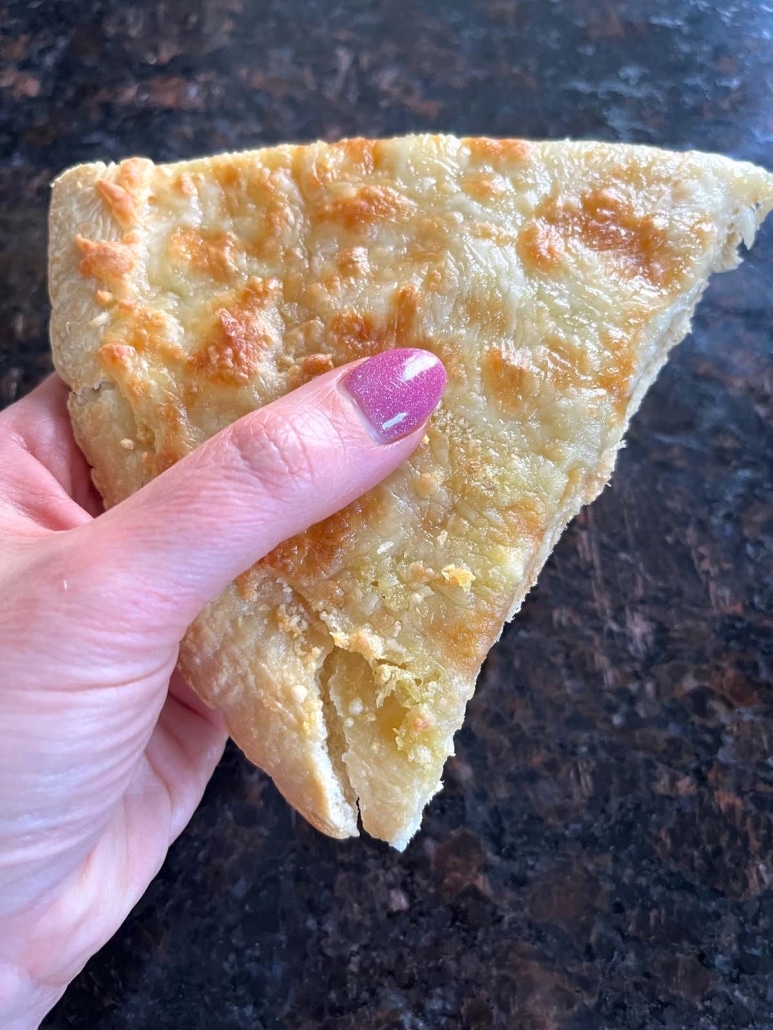 hand holding a slice of Garlic Pizza
